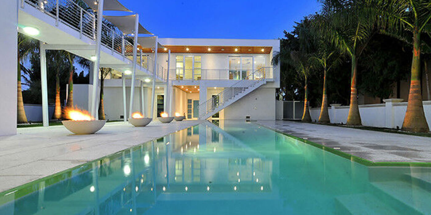 Five gas fire bowls next to a swimming pool in an ultramodern outdoor patio