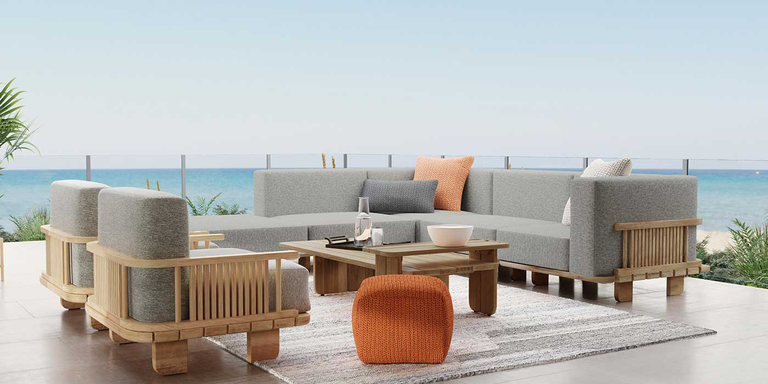 A coastal outdoor patio space with a sectional couch, two chairs, a stool, and a coffee table