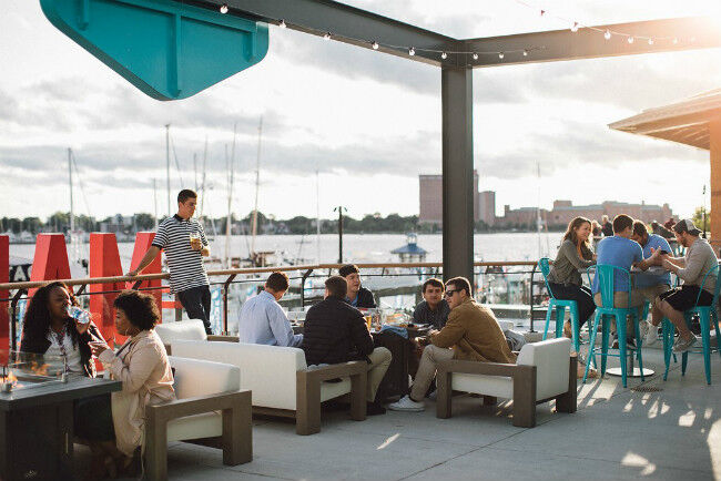 People drinking and dining on an outdoor patio next to the ocean