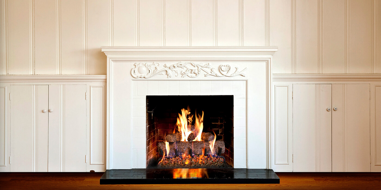 A white hearth with a small square Direct Vent gas fireplace and authentic-looking gas log set
