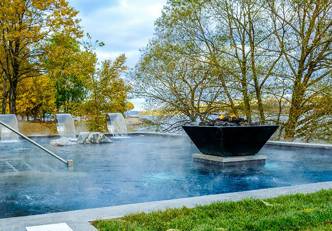 Square black gas fire pit in a vibrant blue pool