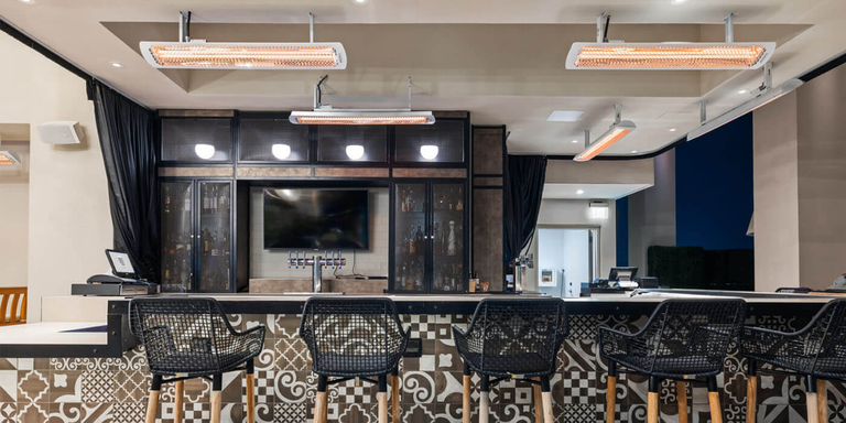 An bar space with several ceiling-mounted patio heaters 