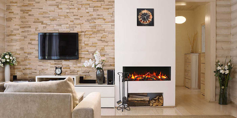 A modern farmhouse-inspired living space with custom, natural stone finished walls, a white accent wall with a linear wood burning fireplace, a wood storage area underneath the fireplace, and black fireplace tools.