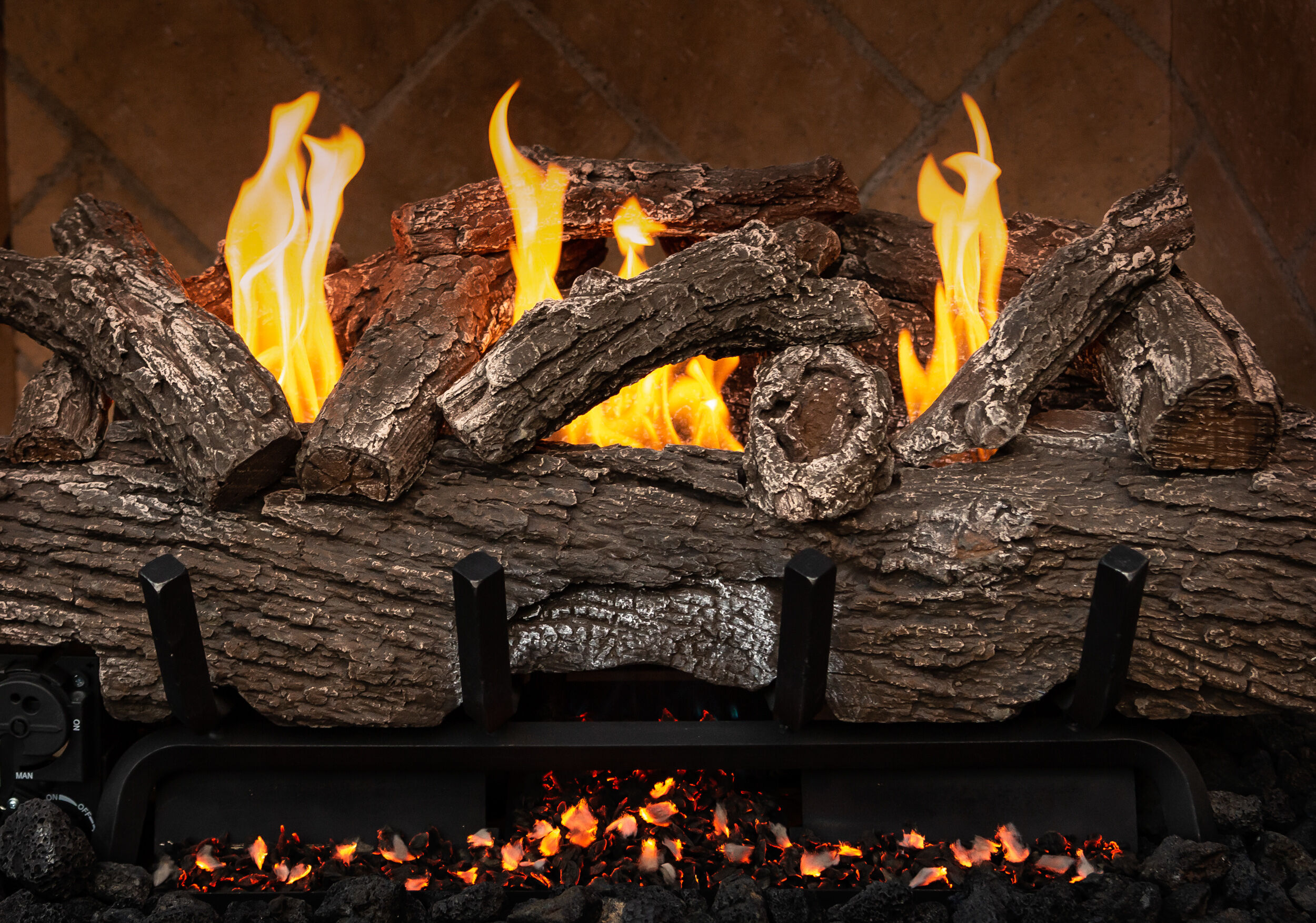 A close-up shot of a rustic, Ventless gas log set with unique twists, cracks, and splits in the bark and bright, yellow flames.