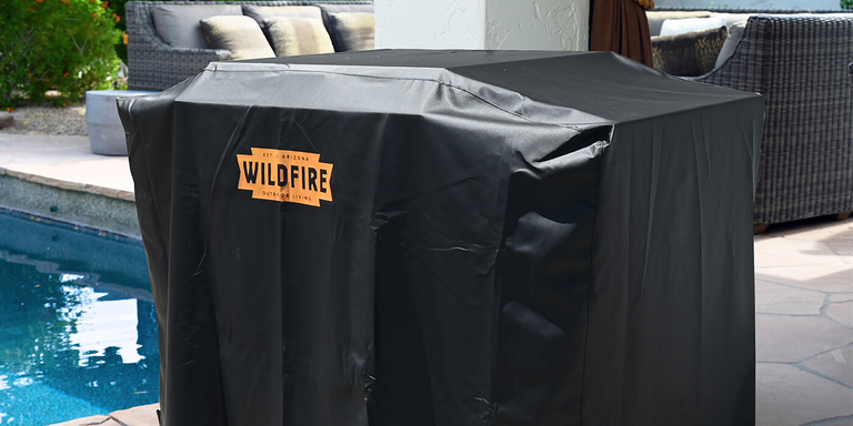 A Wildfire Ranch Pro Cart Mount Gas Grill covered with a matching vinyl Wildfire grill cover