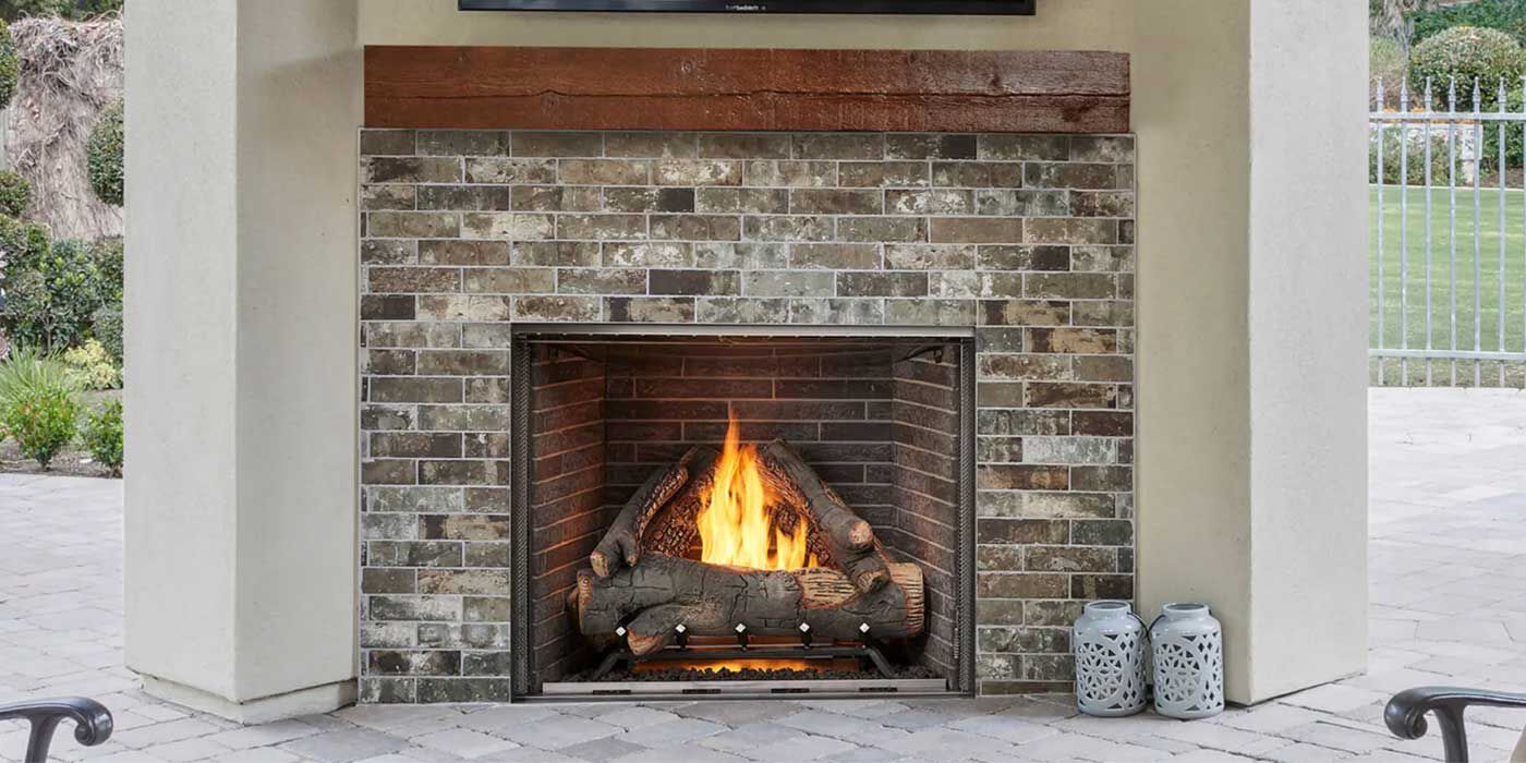 The traditional Courtyard gas fireplace from Majestic features a large, square design with multiple masonry-style firebox liners and two realistic log sets.