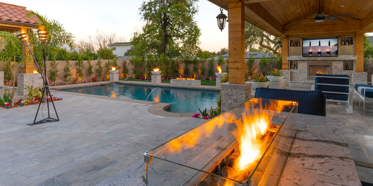 A large covered outdoor patio space with a linear gas fire pit