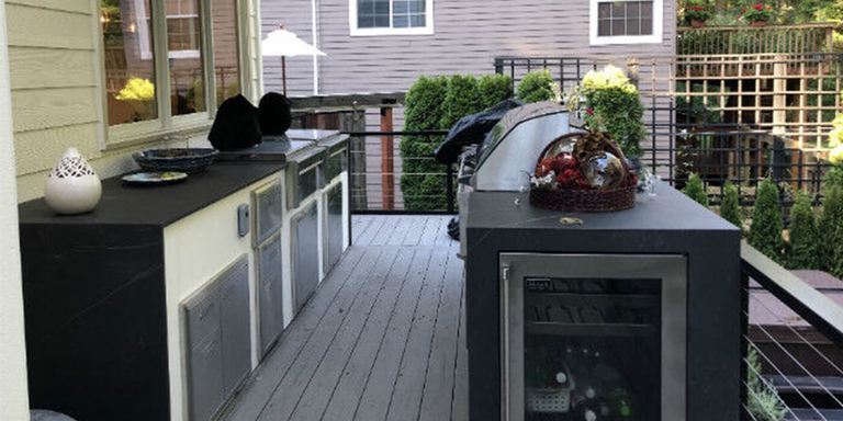 Gray and white outdoor kitchen island with stainless steel components and a built-in grill