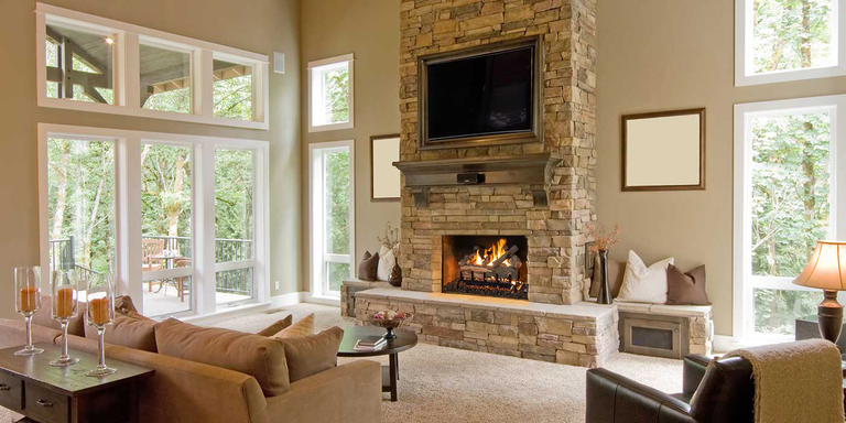 A traditional living space with a natural stone hearth, square fireplace, and rustic gas log set.