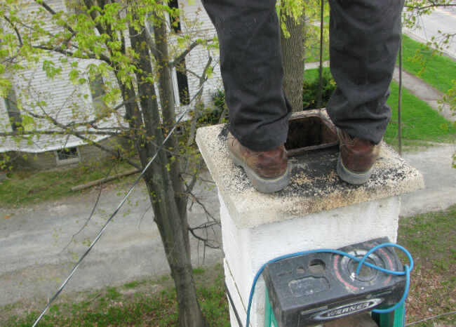 Chimney sweep's feet standing on a white stone chimney