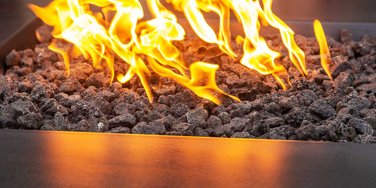 A gas fire pit with black lava rock fire media