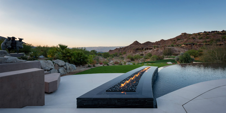A custom-built linear gas fire pit installed on an outdoor patio near a pool