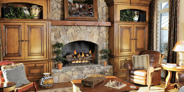 A rustic traditional living room with an arched gas fireplace and a large, charred gas log set