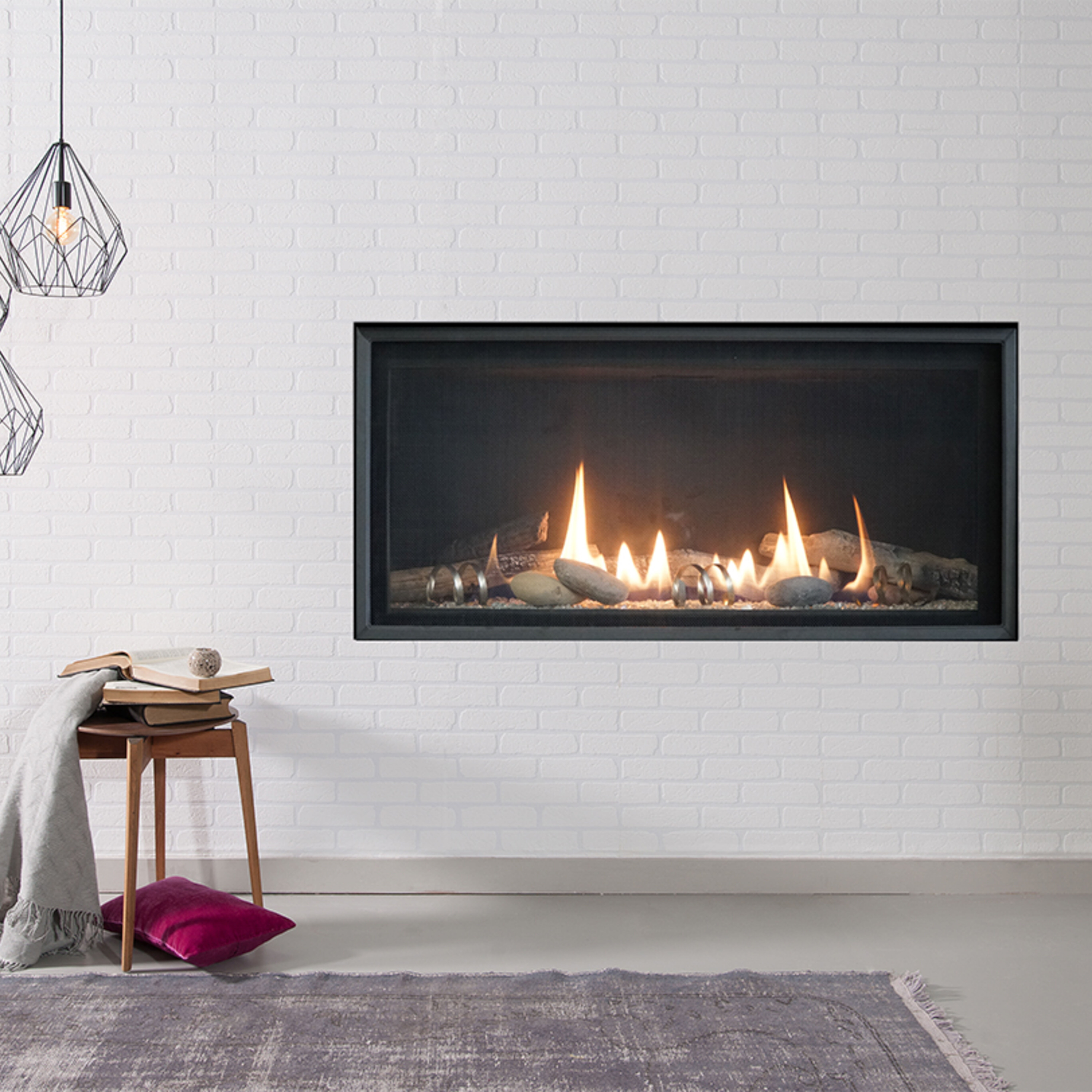 The Empire Loft Series Ventless Gas Fireplace installed on a white wall with modern, geometric and wood accents, a neutral colored rug, and red accent pillows.