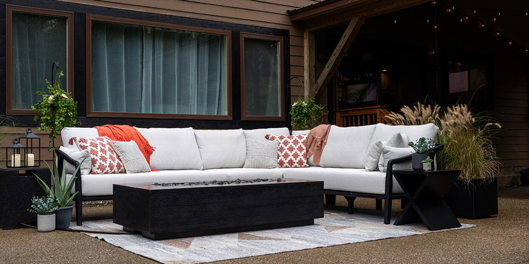 An outdoor patio with a large white sectional sofa and the black linear Zen Gas Fire Pit by FlameCraft
