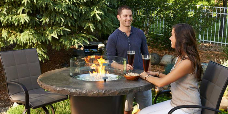 A couple sitting around a counter-height gas fire table
