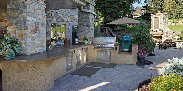 A large custom kitchen island with a stainless steel grill head and matching storage doors and drawers.,