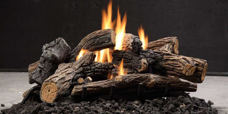 A gas log set with textured brown-gray bark, black lava rock, and orange flames.