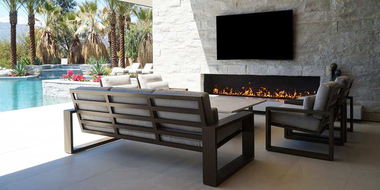 An outdoor patio with lounge furniture and linear Isokern outdoor gas fireplace under a mounted flatscreen TV