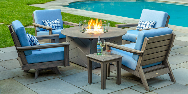 Four outdoor chairs placed around a gas fire pit.