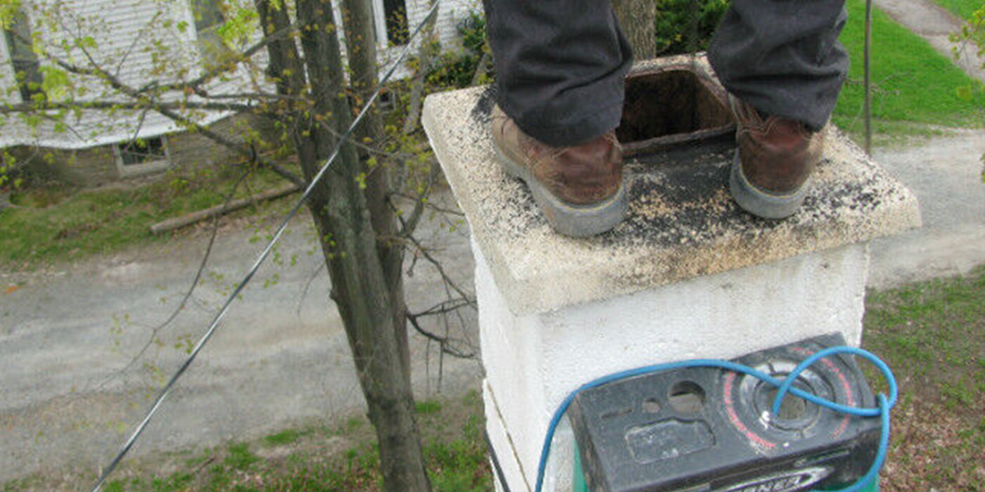 Chimney sweep's feet standing on a white stone chimney