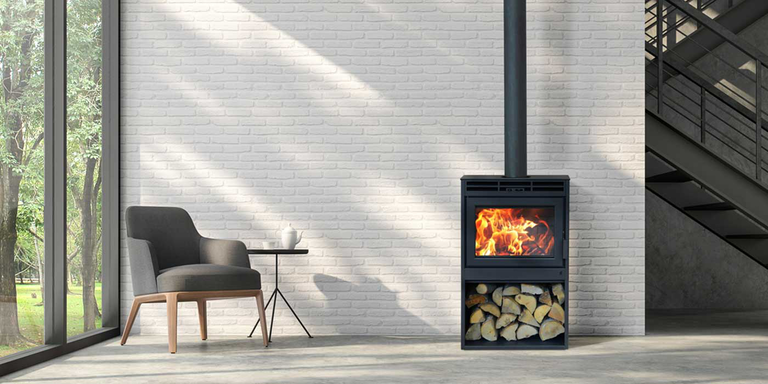 A modern living room with a traditional wood stove against a white brick wall with a single accent chair nearby
