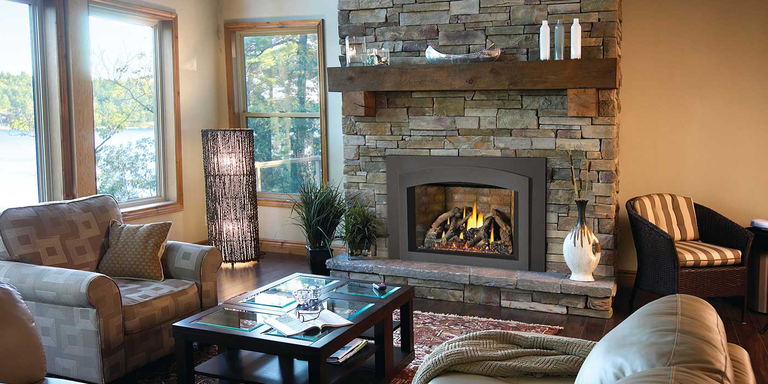 A traditional living space with a custom, natural stone hearth, a wooden mantel, and a square gas fireplace insert with a log set.