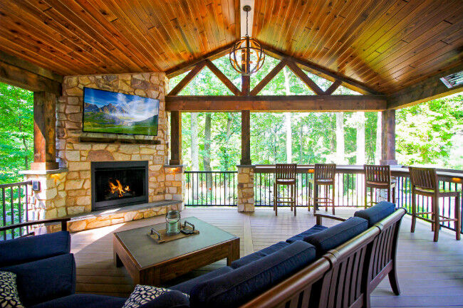 Rustic covered wood deck with outdoor living room and fireplace