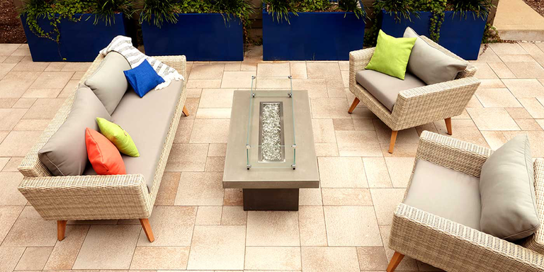 An outdoor patio space with a couch, two chairs, and an outdoor fire pit table