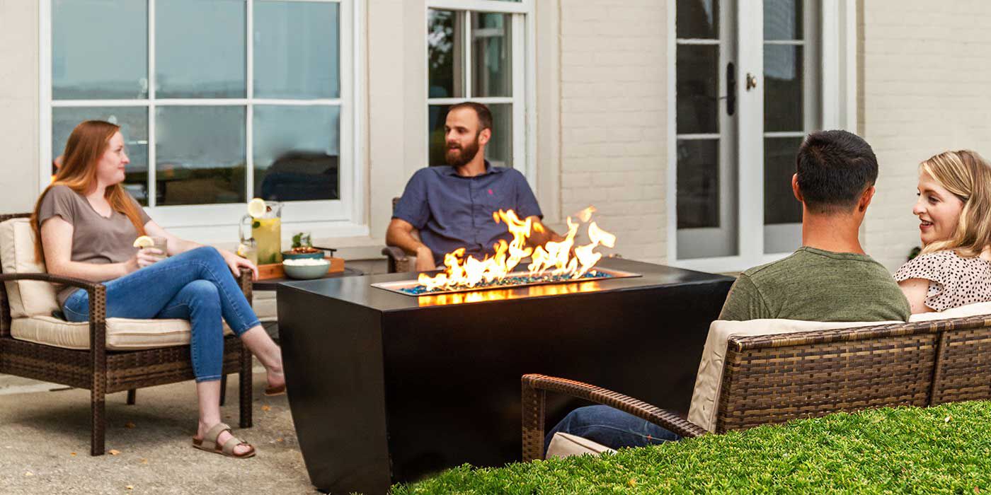 Four people sitting around a chat-height gas fire pit table
