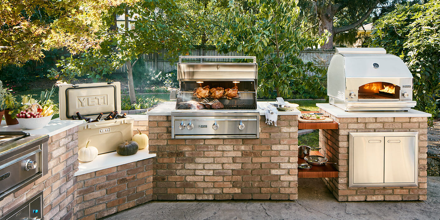 An outdoor kitchen island with a grill, storage, a Yeti cooler, and an outdoor oven.