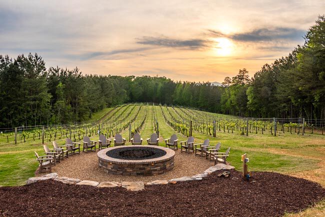 Unlit masonry fire pit in front of a vineyard at sunset