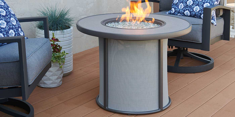 A small aluminum gas fire pit on an outdoor wood deck