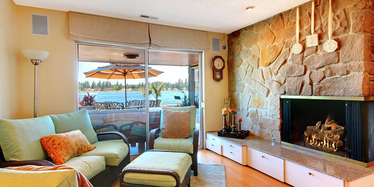 A coastal living space with a natural stone hearth, linear fireplace, and natural-looking, rustic gas log set.