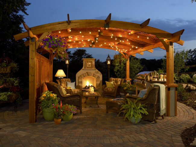 Evening view of backyard patio with gas fireplace and pergola