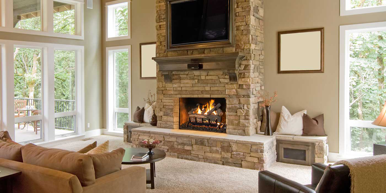 A traditional living room with a natural stone hearth and chimney, and a square fireplace with rustic gas logs.