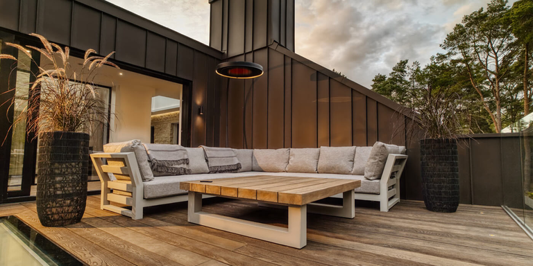 An outdoor lounging space with a sectional sofa and a Bromic Eclipse freestanding patio heater