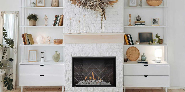 A contemporary living space with a large white stone hearth, built-in shelves, and a square gas fireplace