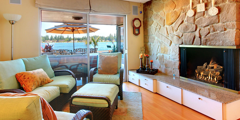 A waterfront living room with a natural stone hearth and a large, traditional gas fireplace with a realistic, rustic gas log set