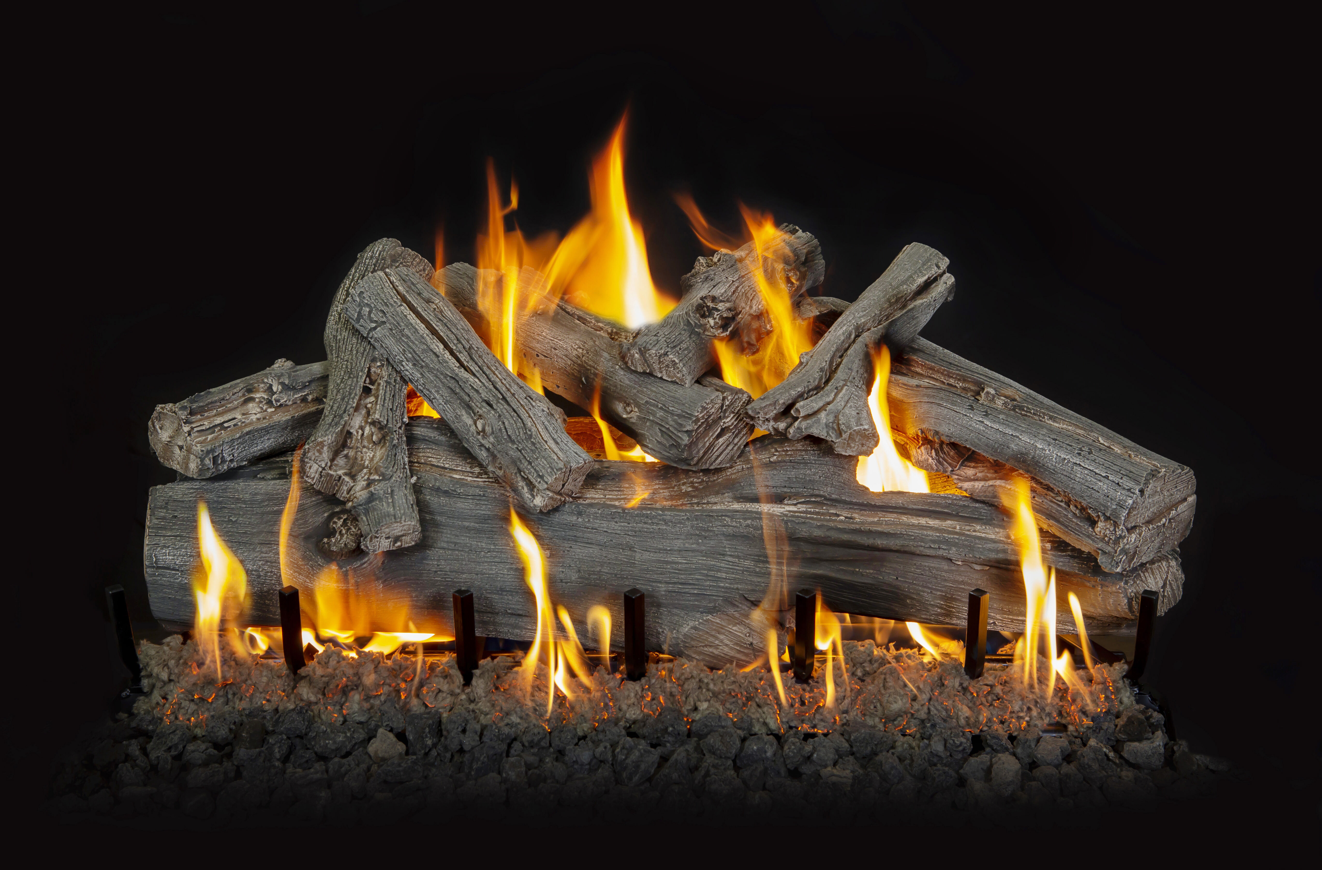 A close-up view of a rustic gas log set with a realistic, natural bark finish and full, campfire-like flames.