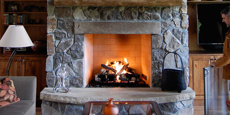 The Isokern B-Vetto Gas Fireplace installed on a rustic, stone hearth with a wooden mantel and traditional-style decor.
