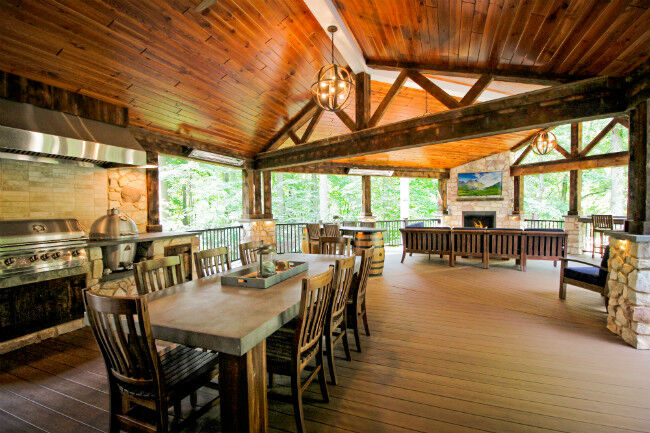 Rustic covered deck with an outdoor kitchen and outdoor living room