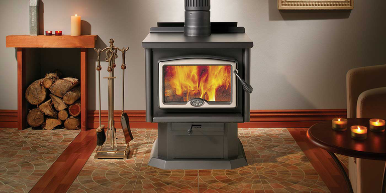 A traditional wood burning stove with a wood storage box and fireplace tools