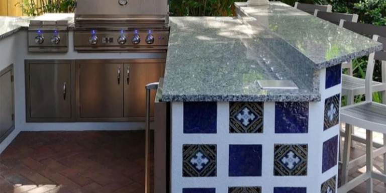 An outdoor kitchen island finished with blue and white patterned tiles
