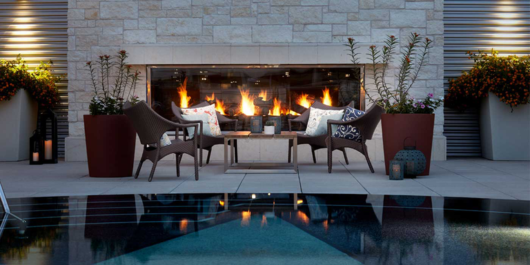 A contemporary, linear indoor-outdoor gas fireplace viewed from an outdoor patio