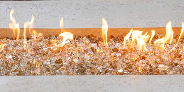 A gas fire pit with reflective, gold-colored fire glass media
