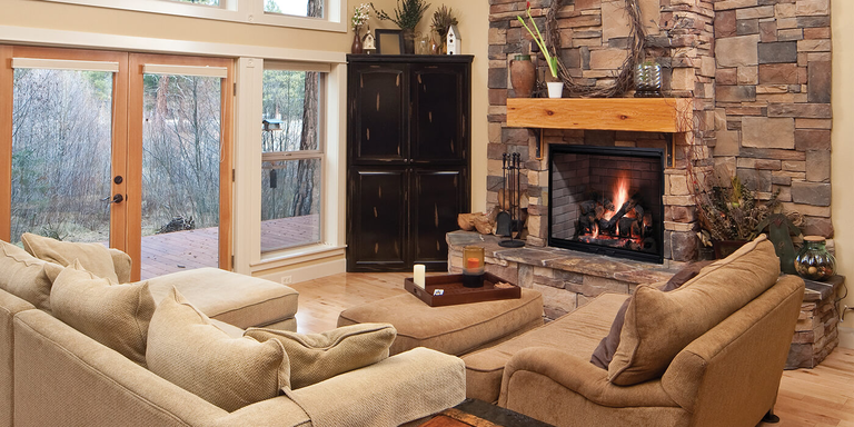 A traditional living space with a large classic wood burning fireplace, stone hearth, and wooden mantel