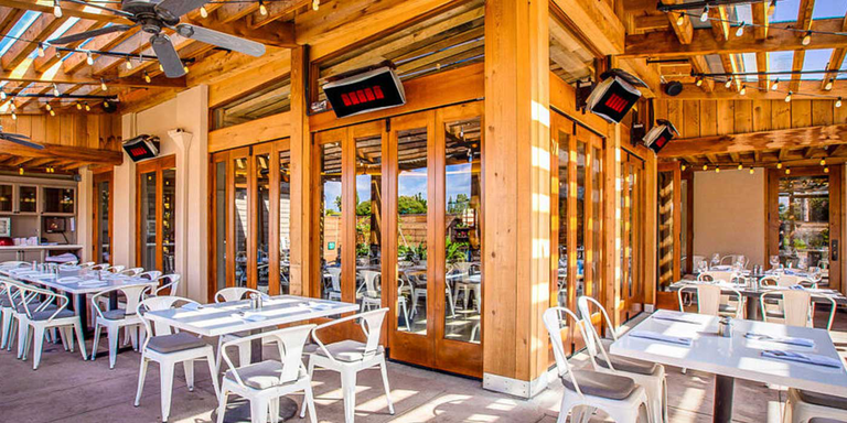 An outdoor restaurant patio with multiple patio heaters installed above the tables