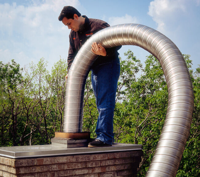 Man Installing Chimney Liner on Roof