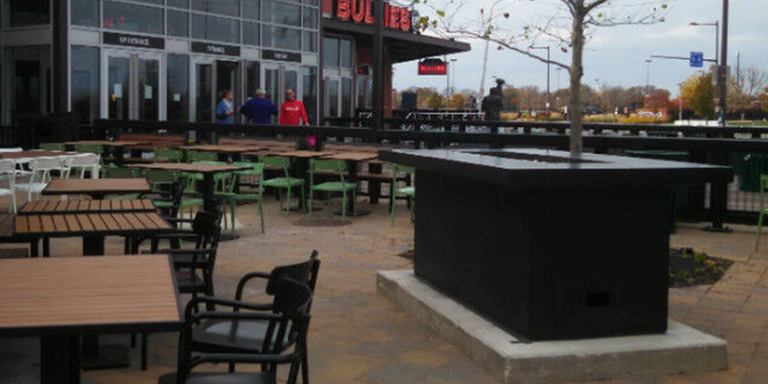 A large black fire pit table on the outdoor patio of the NBC Sports Arena